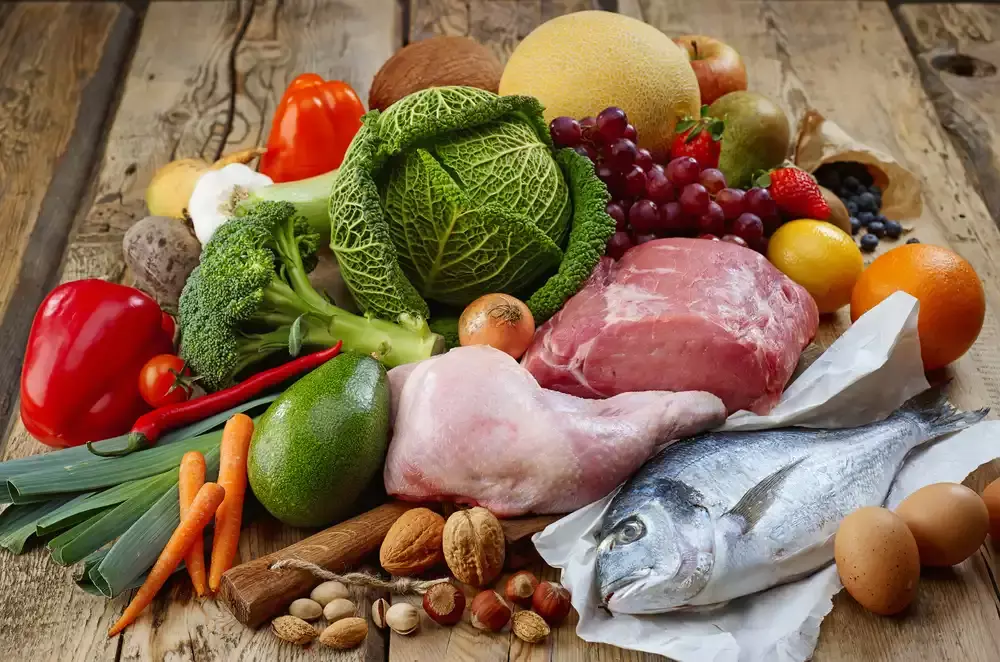 cabbage, chicken, steak, fish, carrots, avocado, bell peppers, melon, grapes, berries, broccoli and nuts sitting on a table