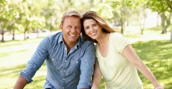 smiling couple on bikes outside