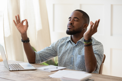 man meditating at his desk to manage stress