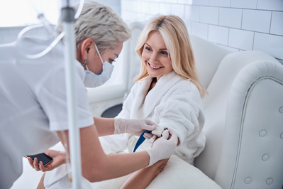 phlebotomist placing iv on a woman who will receive iv nutrient therapy