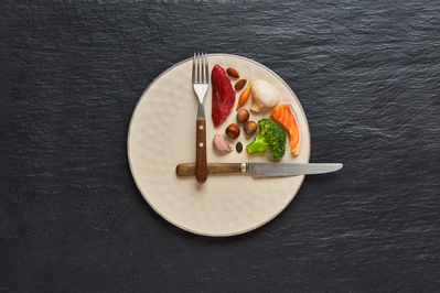 knife and fork set on a plate to look like clock hands with food in between the utensils